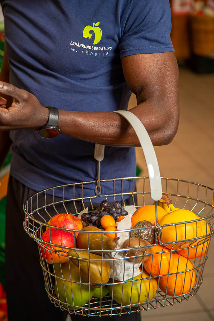 Arm mit Einkaufskorb voller Obst
